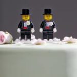 Two male lego figures on top of a wedding cake.